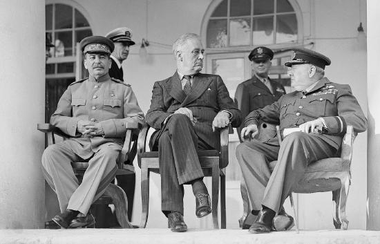 Joseph Stalin, Franklin D. Roosevelt and Winston Churchill on the veranda of the Soviet Legation in Teheran, during the first &ldquo;Big Three&rdquo; Conference, November 1943. In the background are aides to the US President.