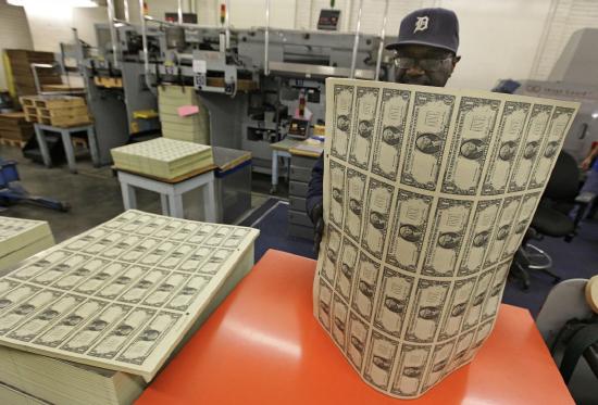Image of a worker at the Bureau of Engraving and Printing with a sheet of printed money.
