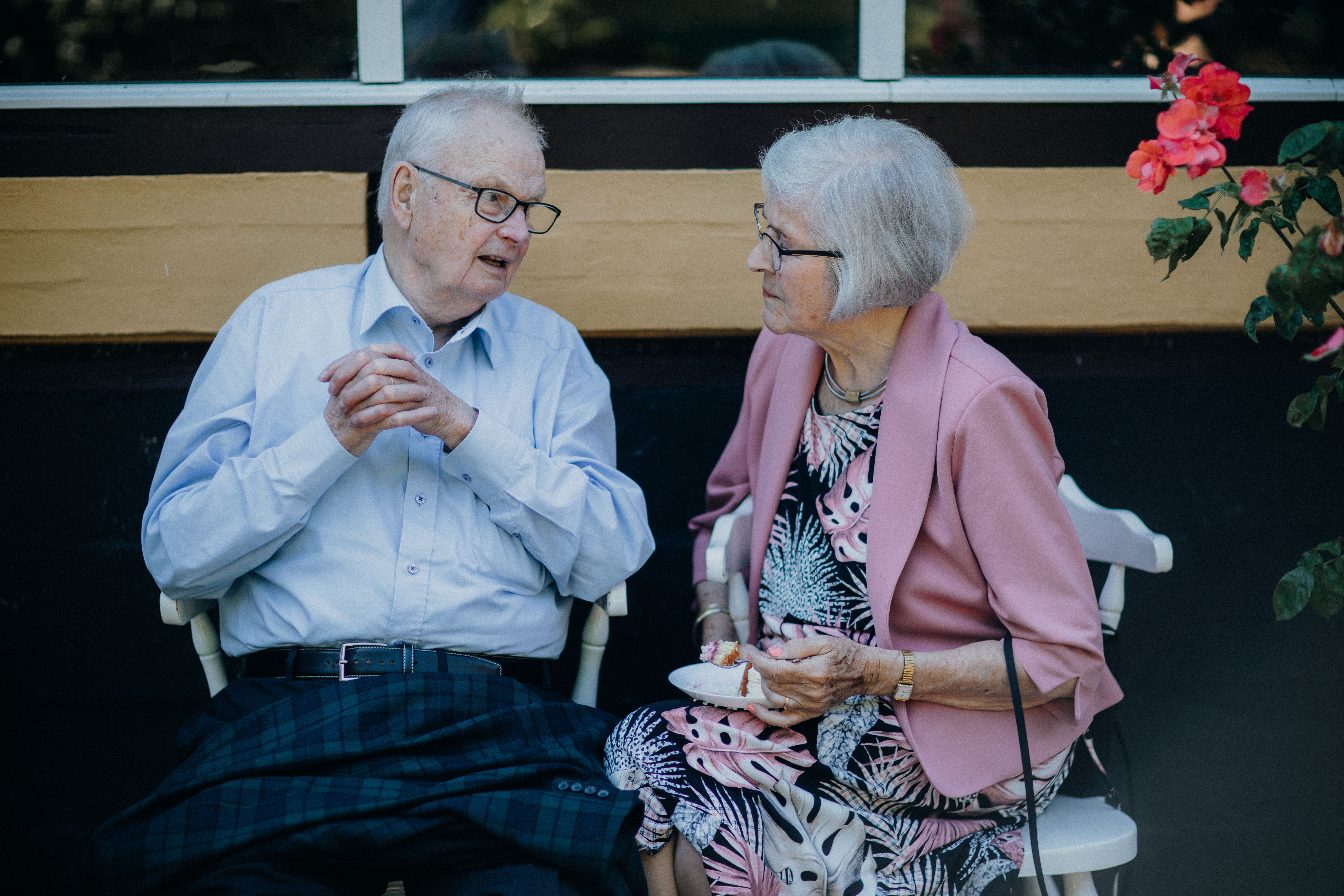 Older adults seated outdoors, engaged in conversation while sharing refreshments.