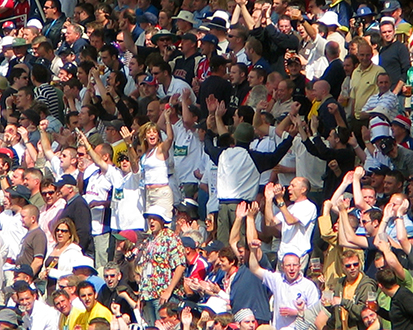 Uma foto de um grande grupo de pessoas sentadas nos bancos do estádio
