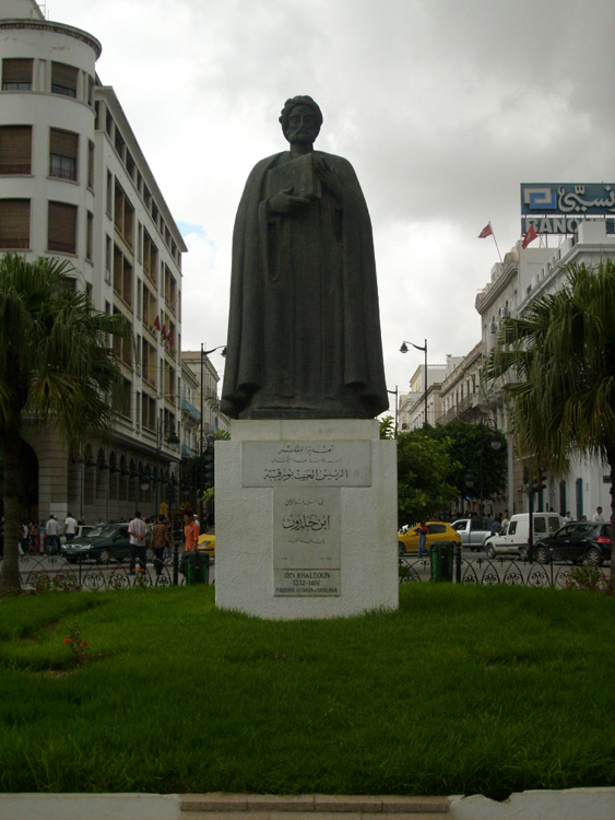 La figure (c) montre la statue d'un homme.