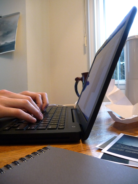 Uma pessoa é mostrada de cima segurando um laptop.