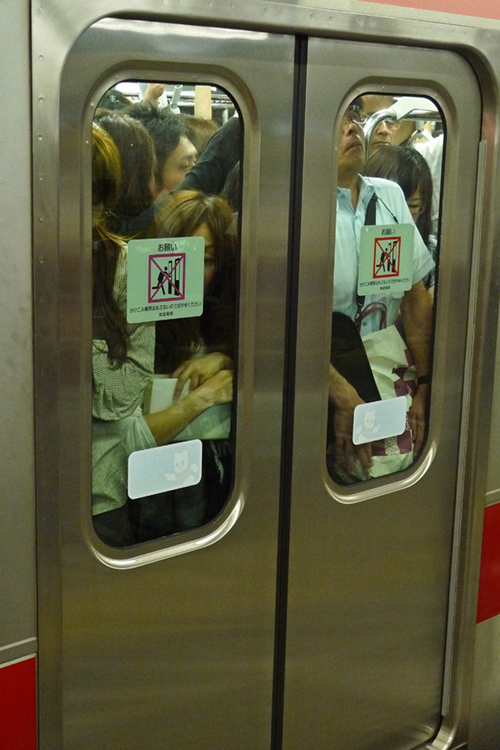 Une foule de personnes derrière les portes fermées d'une voiture de métro est montrée.