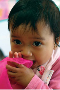 Un niño masticando una manta rosa.