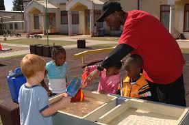 teacher guiding preschoolers in outdoor activity. 