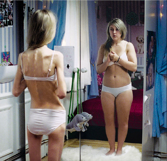 Woman seeing herself in the mirror as fatter than in reality
