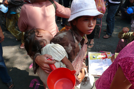 يظهر صبي صغير فقير وهو يحمل طفلة.
