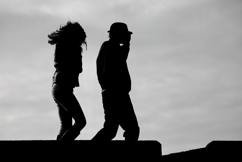 Un homme et une femme marchent dans le vent, un homme devant une femme.