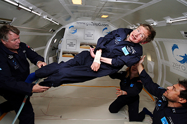 Physicist Stephen Hawking floating in zero gravity, supported by three NASA astronauts