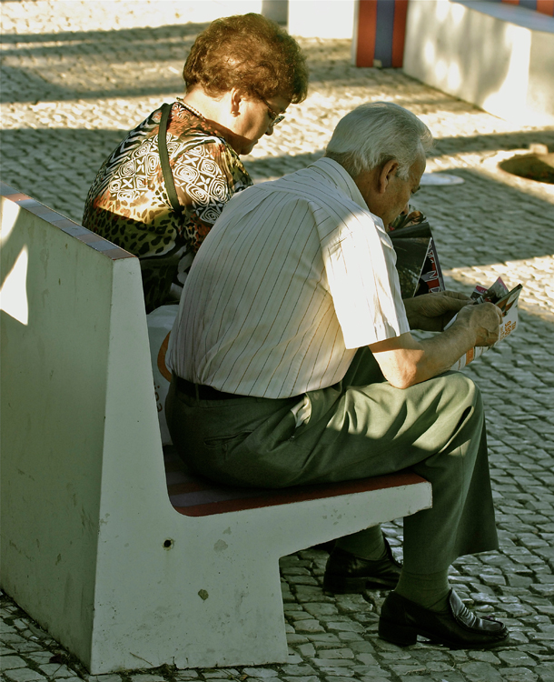 Um homem e uma mulher idosos são mostrados sentados em um banco.