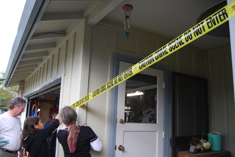 أشخاص يضعون شريط مسرح الجريمة حول المنزل.