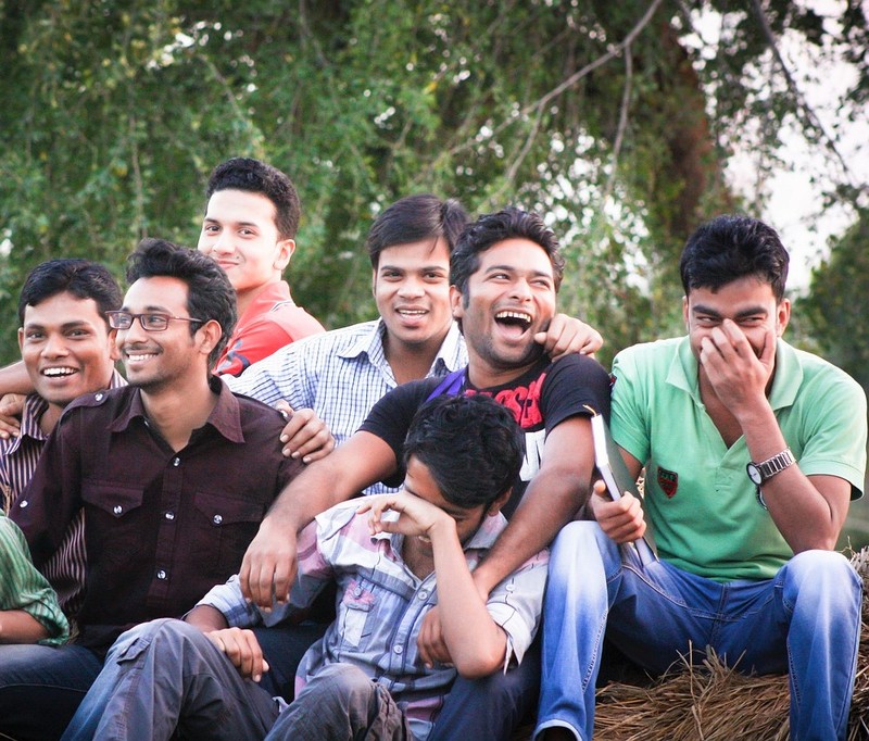 A group of young men sit together laughing and smiling.