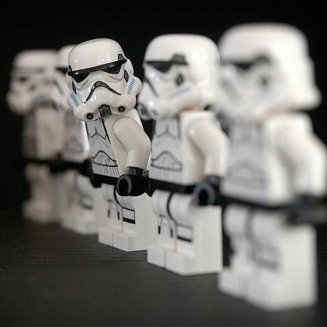 A line of identically dressed stormtroopers from the Star Wars films. One stormtrooper is stepping out of formation and looking at the others in the group.