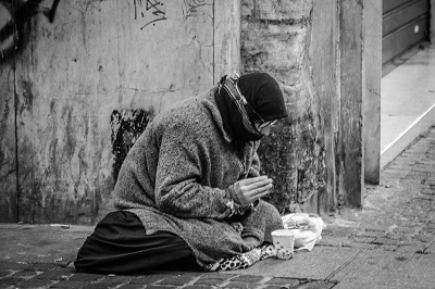 Man Praying on Sidewalk with Food in Front.