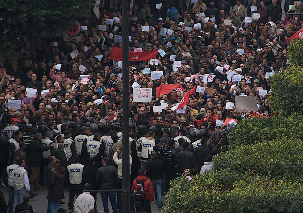 Um grande grupo de pessoas marchando em protesto.
