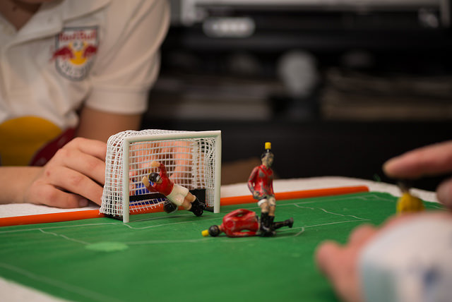 Close-up of two people playing with figurines on a miniature soccer field