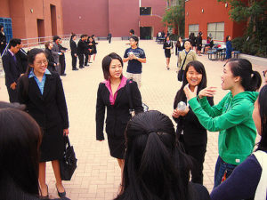 group of young women, many in business suits, standing in a loose circle outdoors