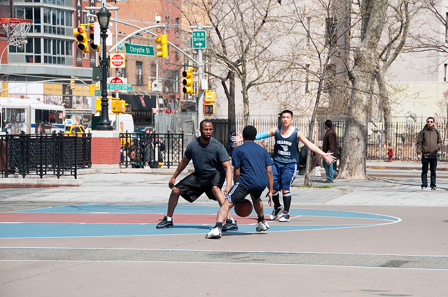 Three young men playing basketball in an urban park