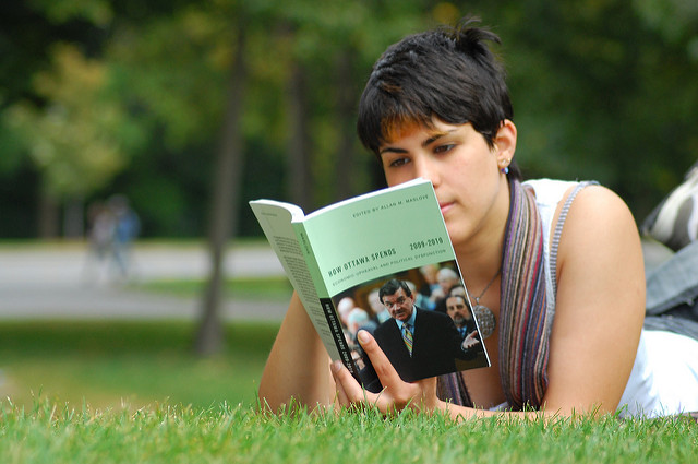 Photo of woman lying on grass, reading "How Ottowa Spends 2009-2010"