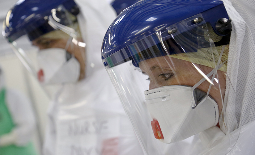 Cette photo montre des travailleurs médicaux portant un masque facial et des gants qui s'entraînent à se protéger afin qu'ils puissent pénétrer dans des zones infectées.