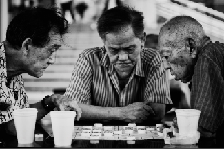 Three people at a table leaning over a board game.
