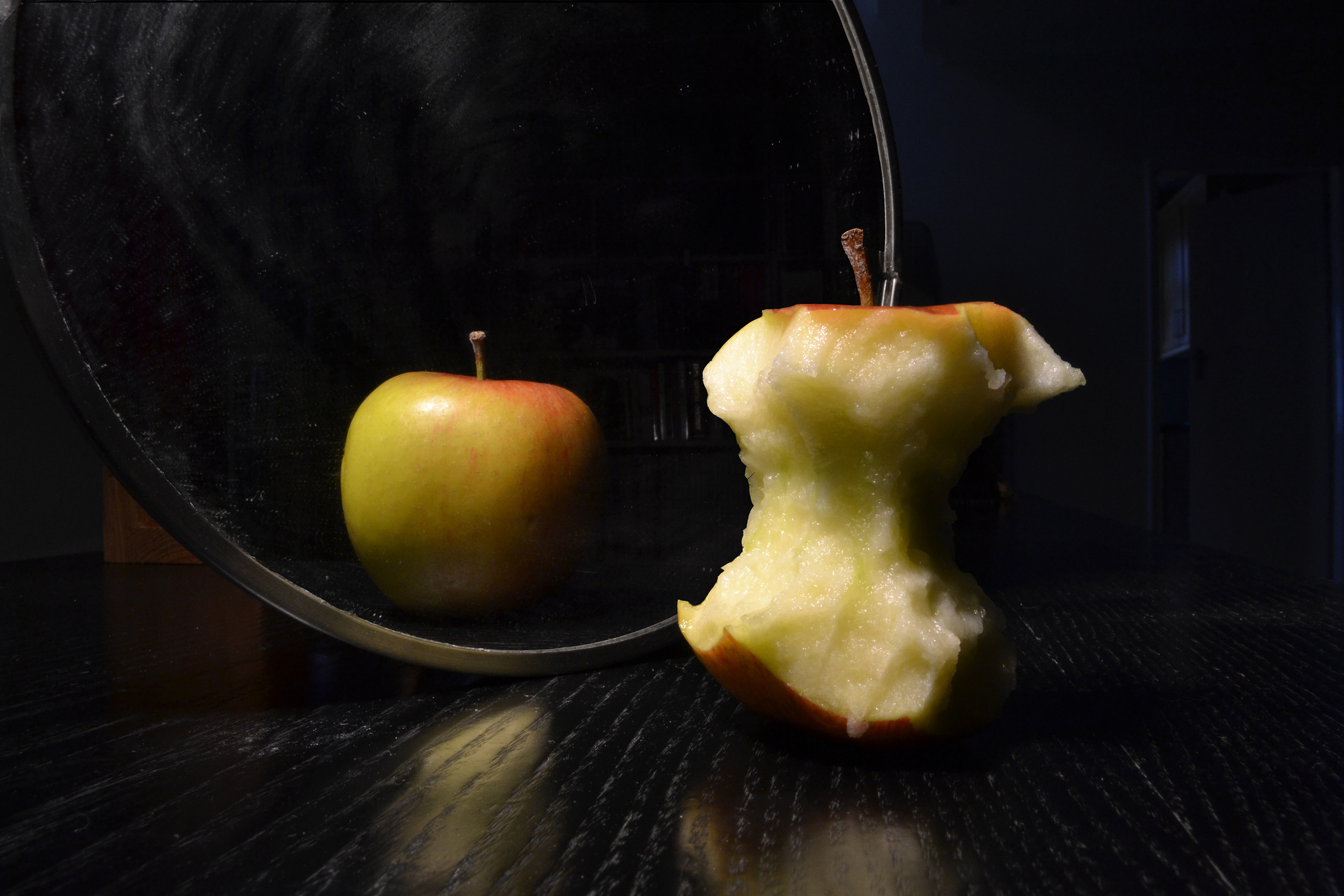 Apple in the mirror. The apple is whole but the reflection is eaten.