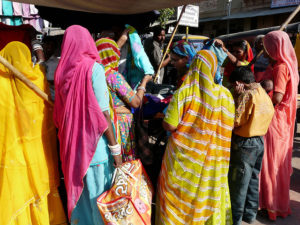 Photo showing the backs of women wearing saris while shopping outside in India.