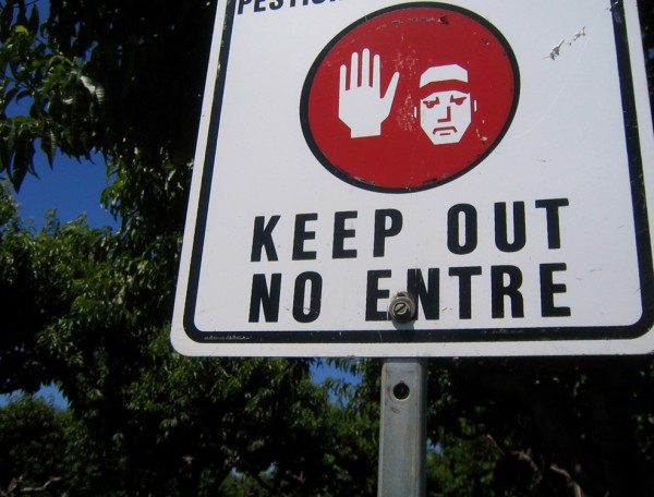 A street sign with text in both English and Spanish reading 'KEEP OUT' is shown.