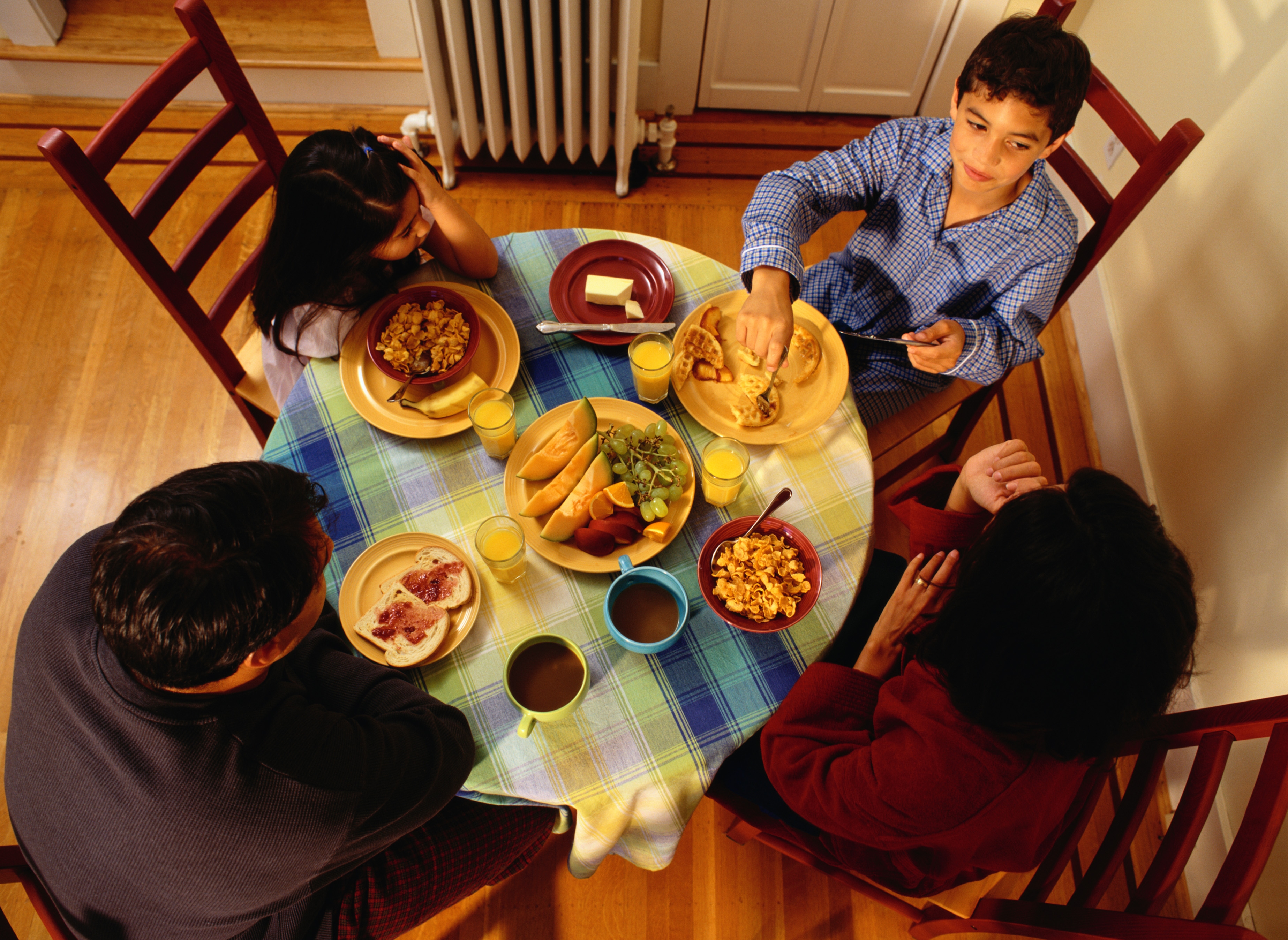 A family sits around a round table eating a meal together.