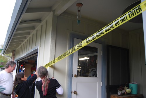 People placing crime scene tape around the front of a house.