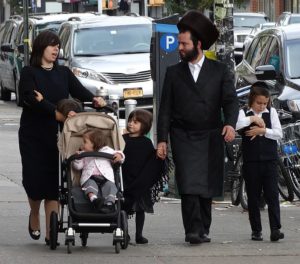 Family in traditional Hasidic Jewish dress walking down the street.