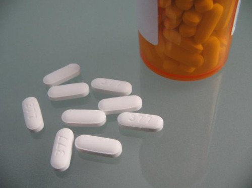 White, oval-shaped pills next to a pill bottle are shown here.