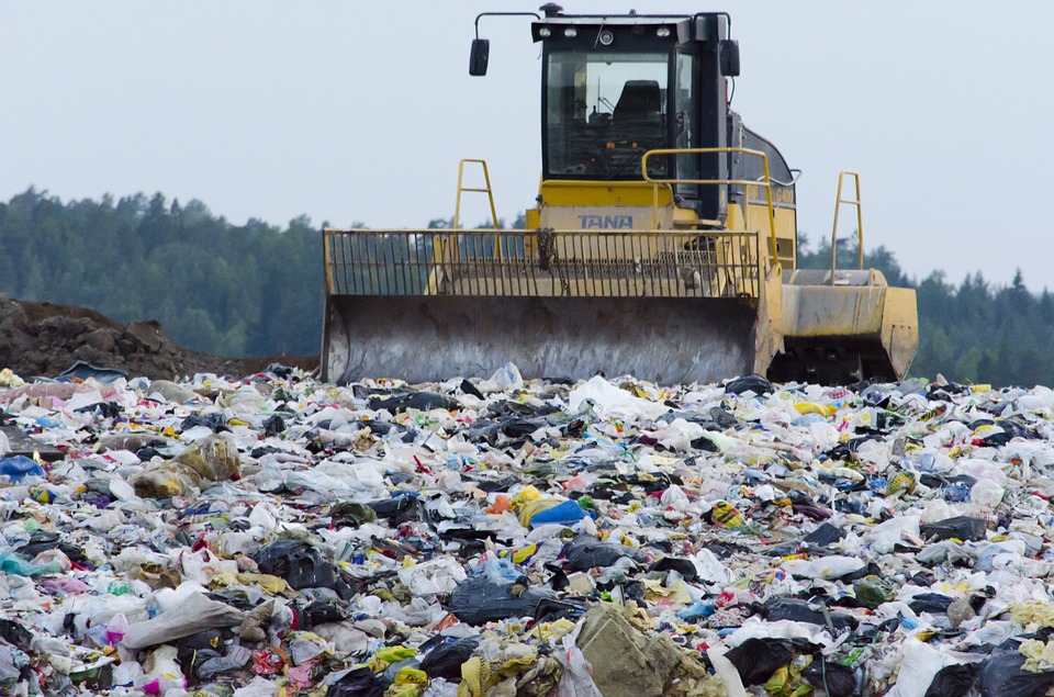 The Garbage Waste Management Waste Society Landfill. A truck plows through heaps of trash.