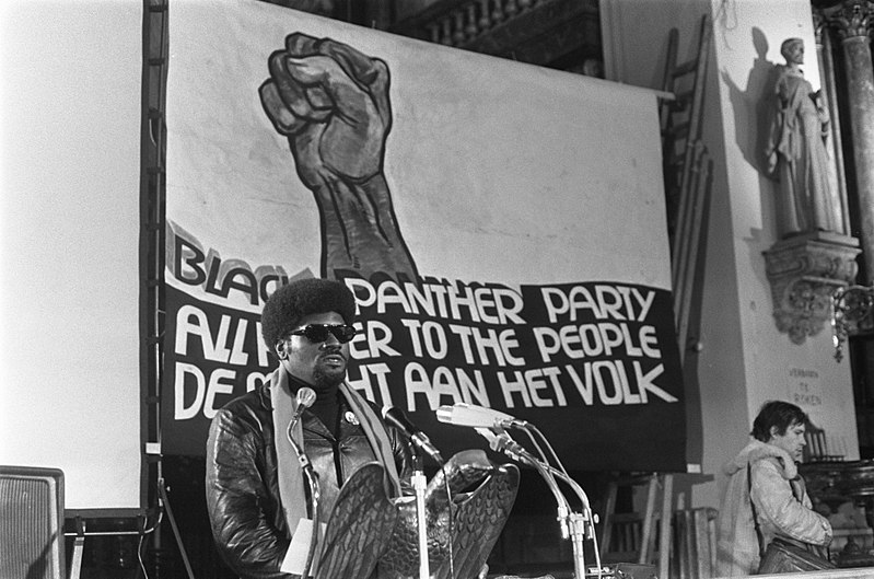 Elbert Howard in front of a Black Panther sign giving a lecture in Amsterdam.