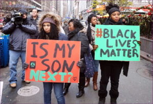 Protestors holding a poster, one that says, "Black Lives Matters" and "Is my son next?"