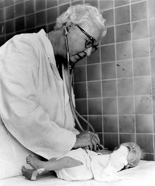 Black and white photo from 1966 of Virginia Apgar listening to a newborn heartrate.