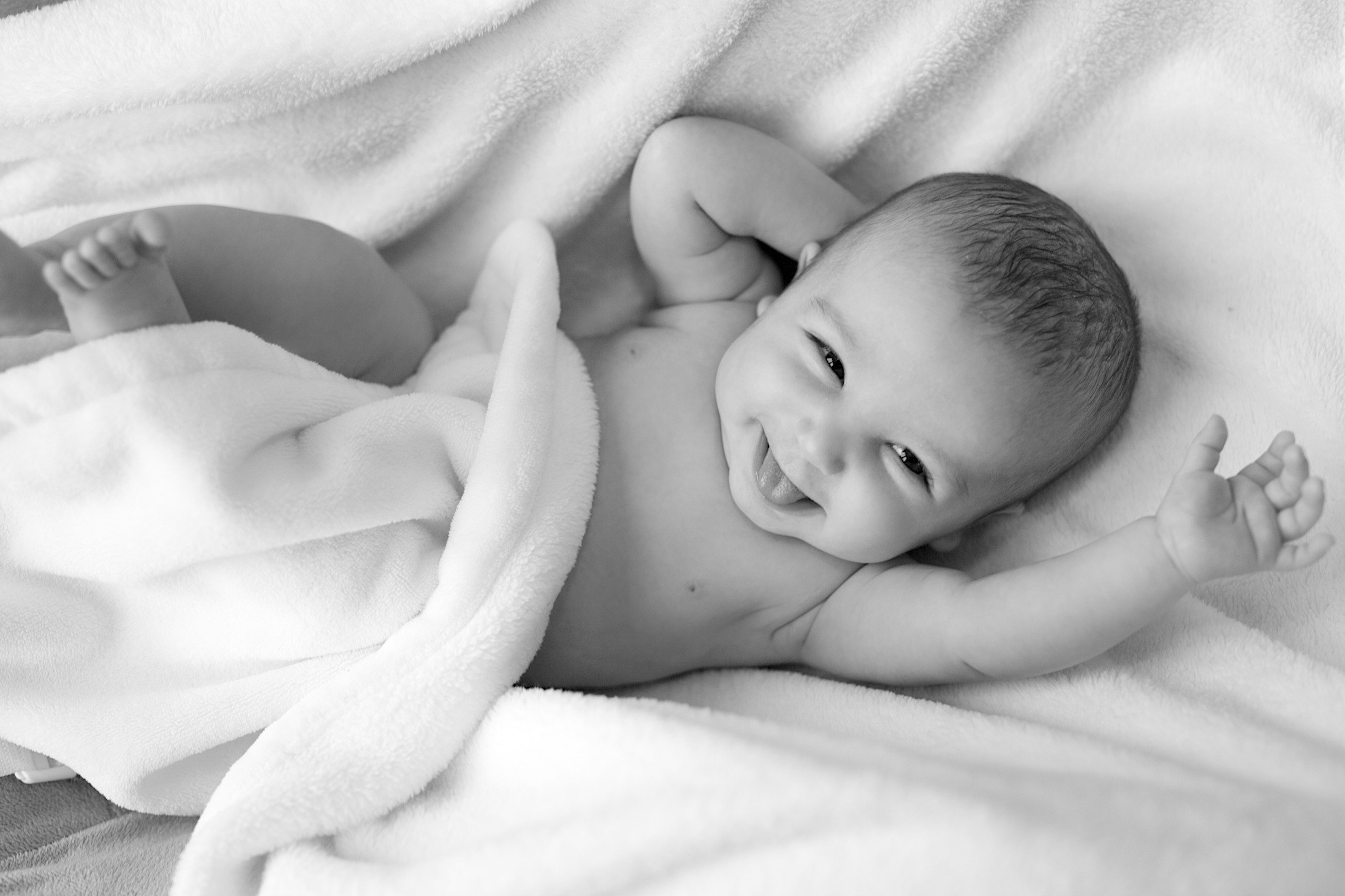 An infant laying in a blanket smiling