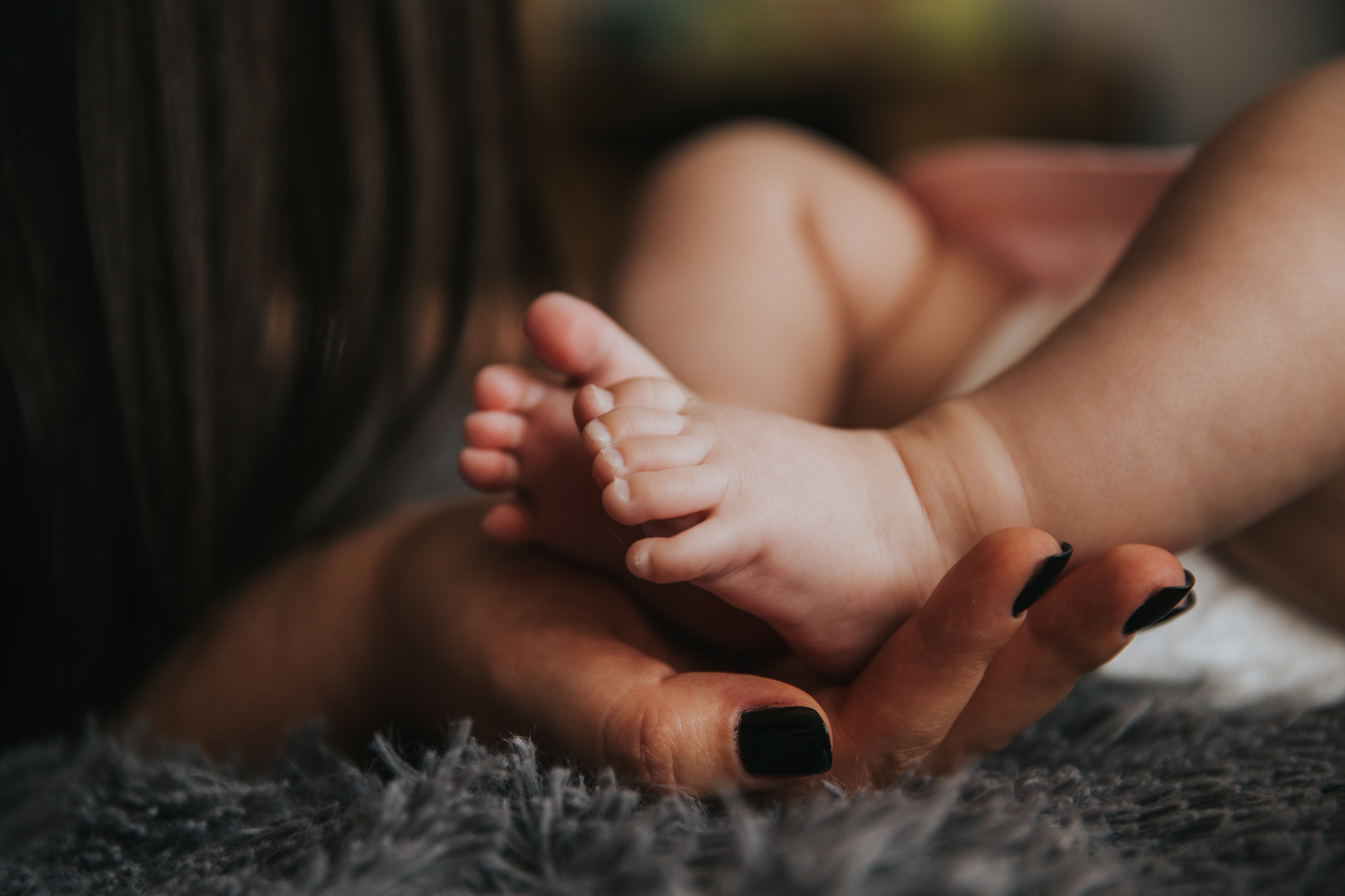 A mother gently holds her infant's feet.