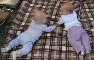 Two infants lying on their stomachs looking at each other