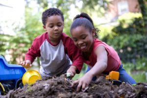 A boy and girl are seen playing in the dirt
