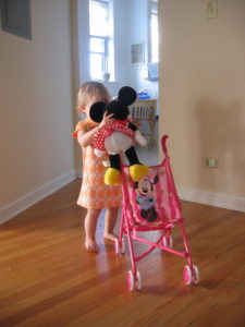 A girl is seen playing with a doll and stroller
