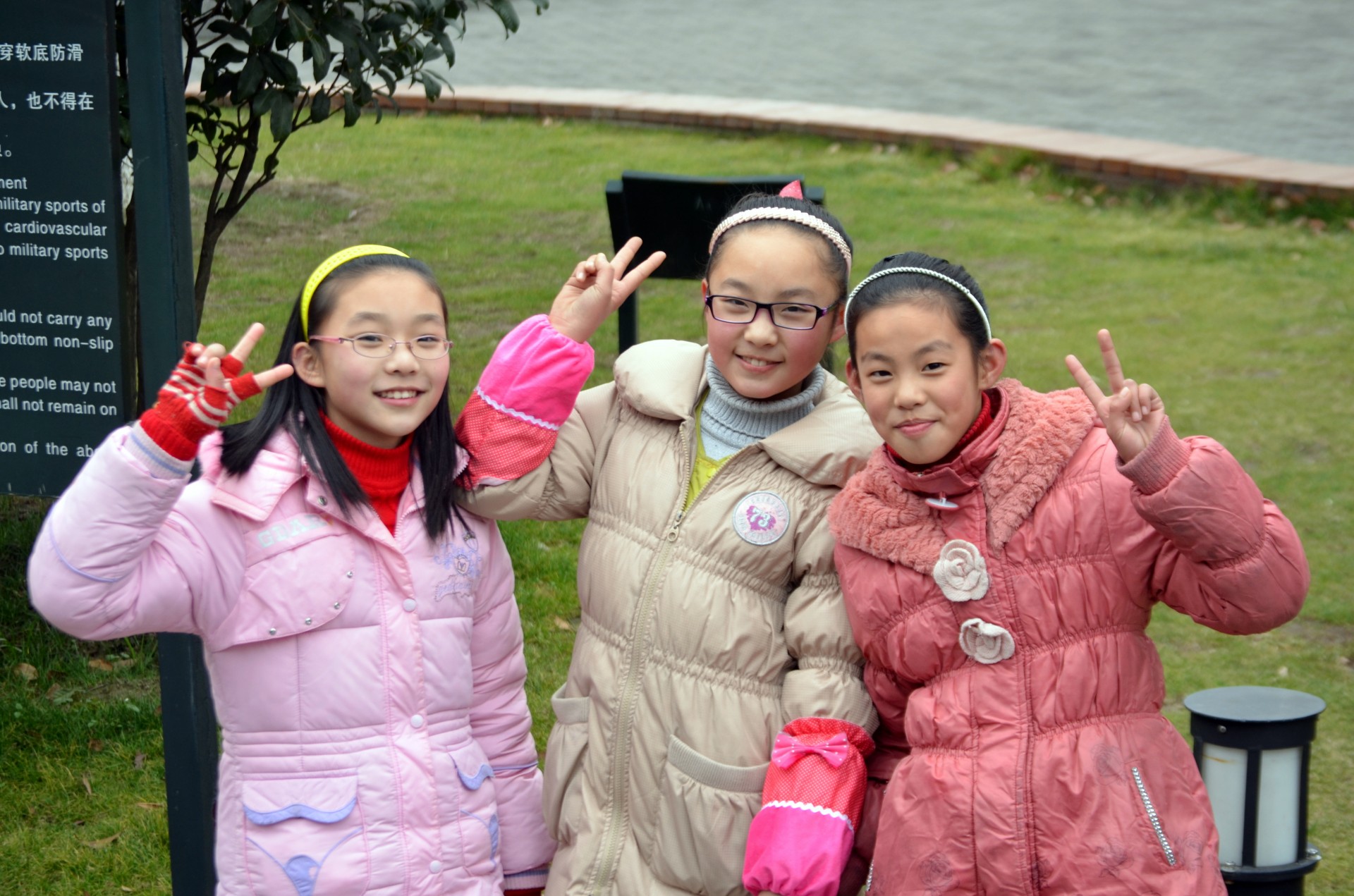 Three smiling girls posing with peace signs for a picture.
