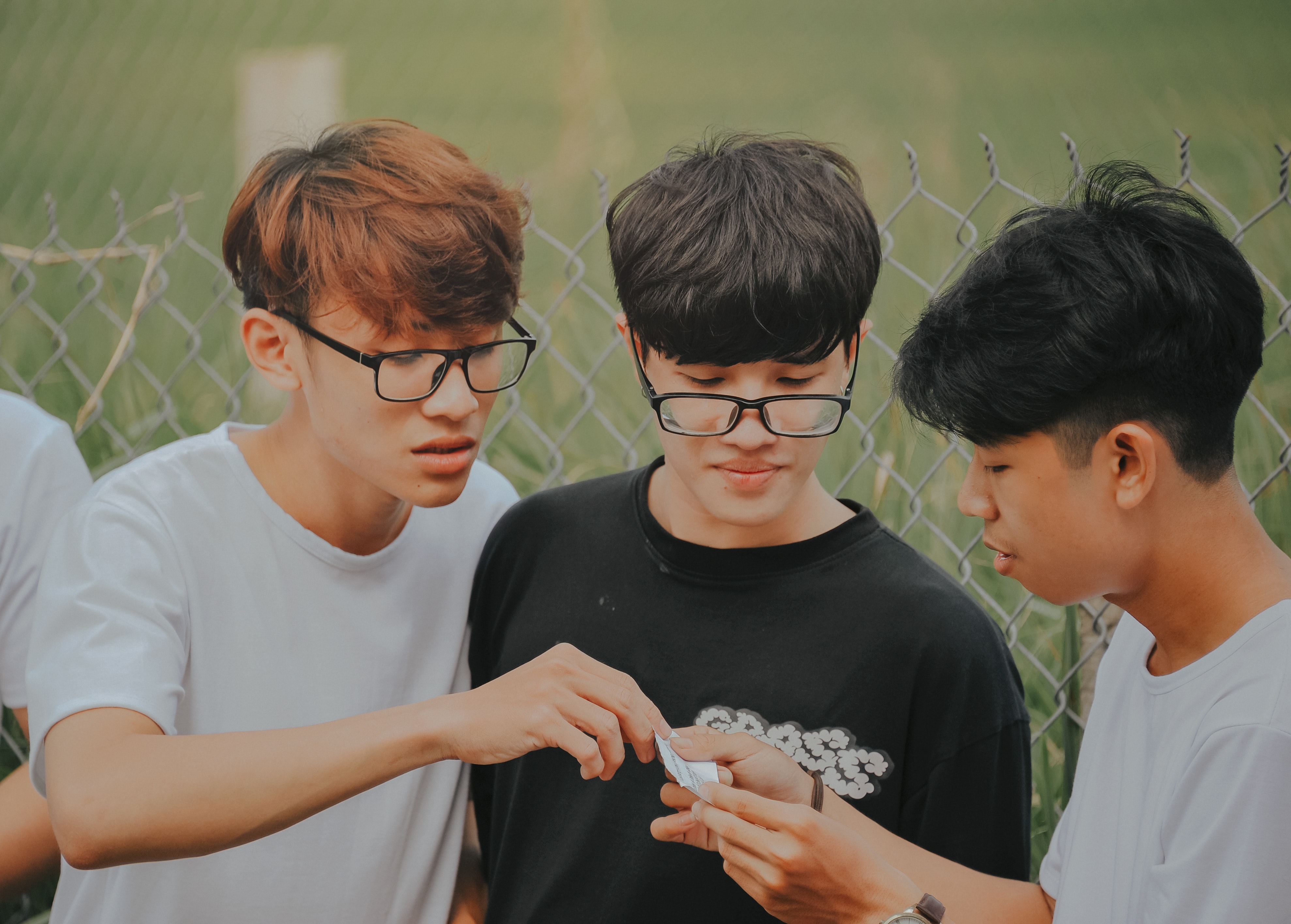three adolescent boys look at a note together