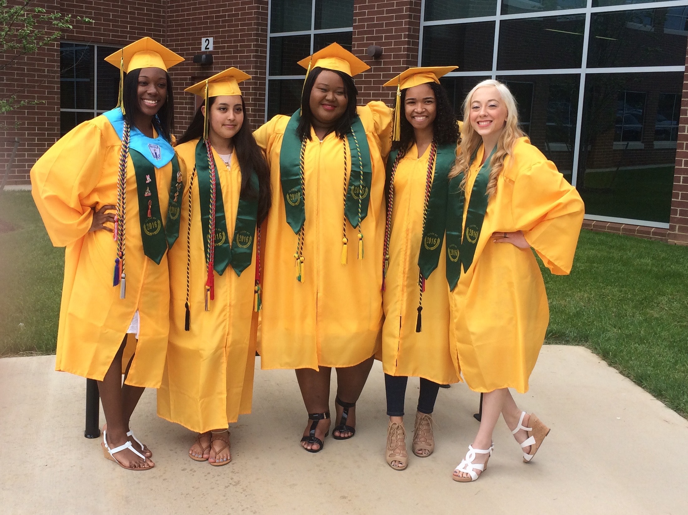 Five friends from the same sorority posing in graduation gowns.
