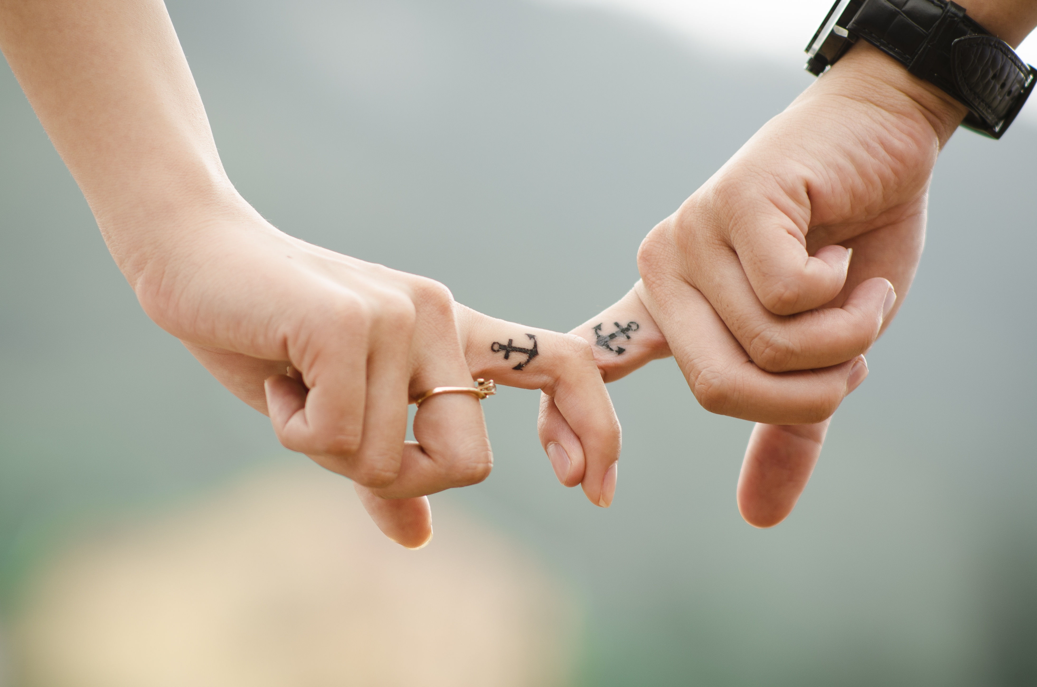 2 interlocking fingers with matching tattoos
