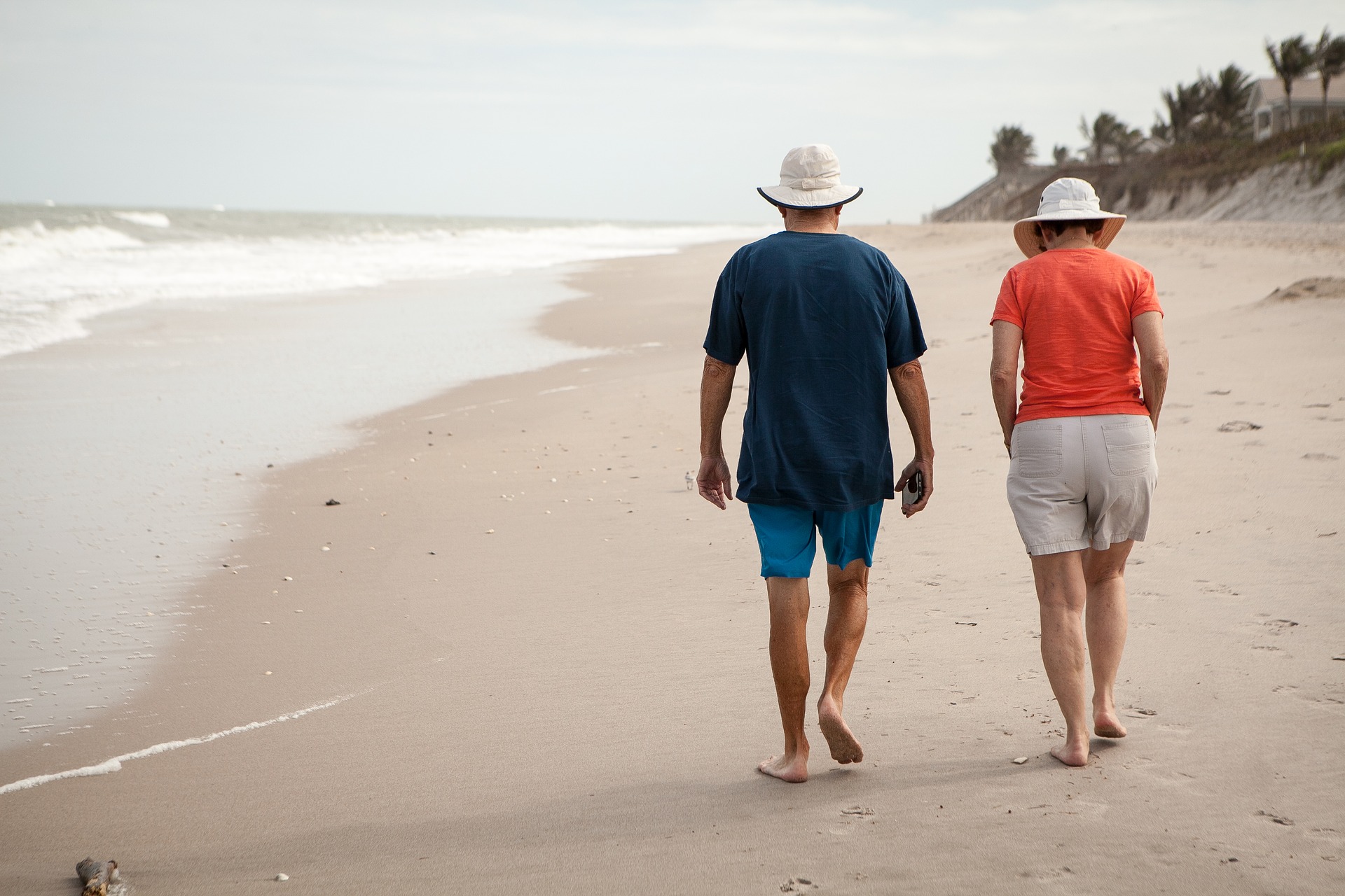 couple in their late 50s taking a walk on the beach.