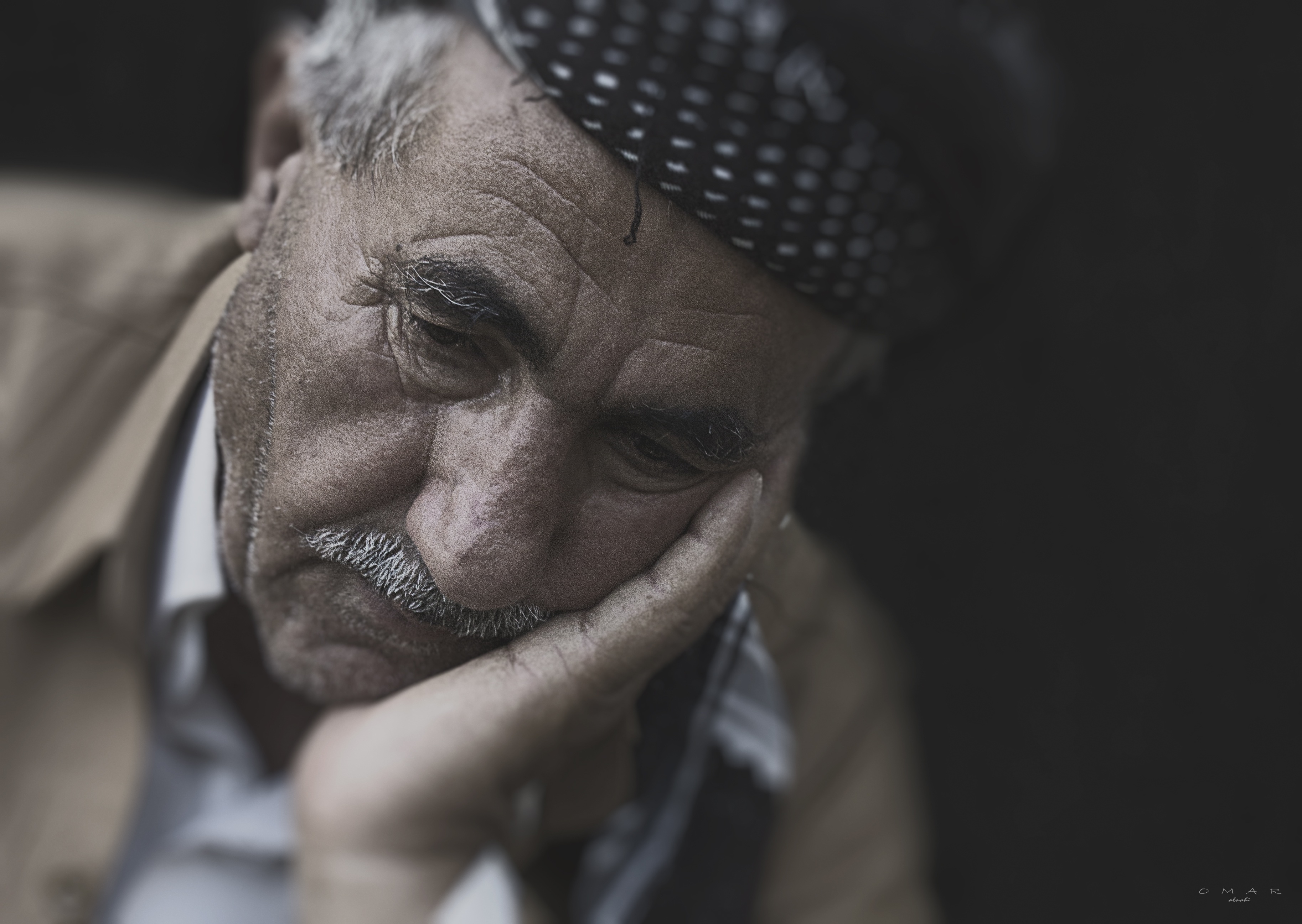 Elderly man resting his head in his hand, looking forlorn.