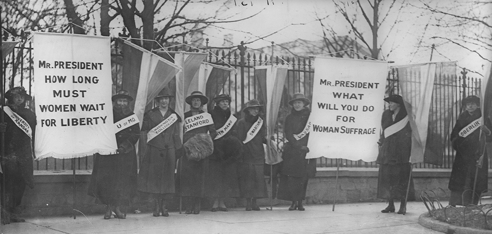 La figure (a) montre les marcheuses pour le suffrage féminin.