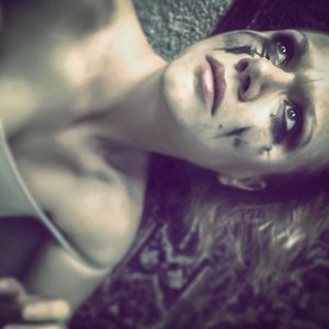 A distraught looking woman lies on the floor with makeup smeared across her face." title="A distraught looking woman lies on the floor with makeup smeared across her face.