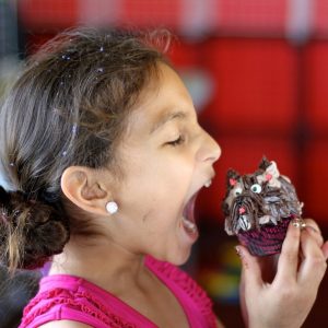 A girl prepares to take a big bite out of a cupcake.